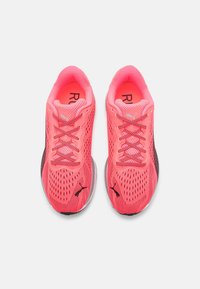 Baskets de sport en rose néon avec un dessus en maille, des accents noirs, des lacets ronds, un col rembourré et une semelle grise, conçues pour le confort et la respirabilité.