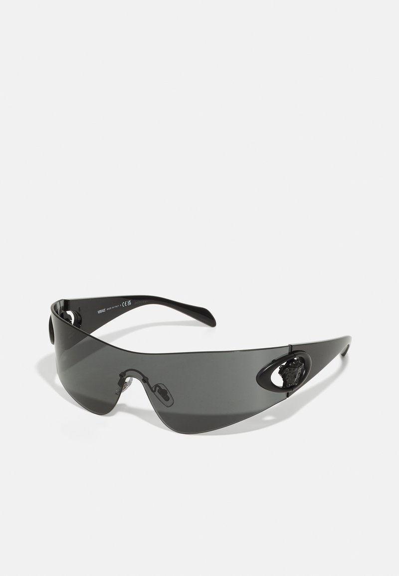 Ochelari de soare negri, supradimensionați, cu un design elegant, lentile curbate și un accent în formă de cap de leu pe laterale. Textură netedă și stil minimalist.