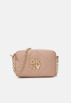 Petit sac à main rectangulaire beige matelassé avec logo DKNY doré et bandoulière chaîne dorée sur fond blanc.