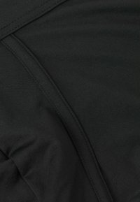 Černá látka s hladkou texturou, s jemnými švy a přiléhavým střihem. Materiál působí lehkým a elastickým dojmem.