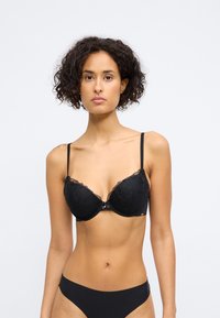 Sutiã push-up de renda preta com padrão floral, suporte mediante a aros, alças ajustáveis e detalhe em laço no centro. Acabamento de tecido suave.