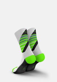 Performance socks in white, featuring green and black stripes, with green accents at the heels and toes. Made of textured material.