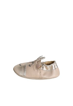 Soft beige baby shoe with metallic toe and heel, decorated with closed eyes, ears, and a small flower on top.