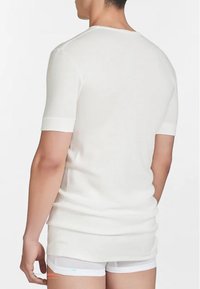T-shirt bianco a maniche corte con scollatura a girocollo, vestibilità slim e texture liscia, caratterizzato da un design minimalista senza loghi o motivi visibili.