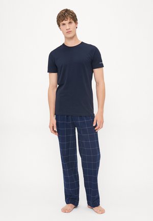 T-shirt bleu marine à manches courtes associé à un pantalon de pyjama bleu marine à carreaux comportant un motif de grille avec des lignes blanches. Les deux vêtements sont amples.