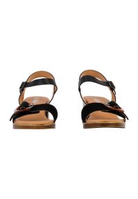Schwarze Wildledersandalen mit verstellbarem Riemen, offenem Zehendesign, Holzabsatz und dekorativem Schleifenakzent an der Vorderseite.