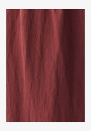 Materijal u boji hrđe sa teksturiranom, naboranom površinom. Tkanina izgleda mekano i lagano, pogodna za prekrivanje ili slojeve.