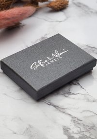 Grå tekstureret smykkeæske med glat overflade, der har det hvide skriptlogo "Sofia Milani Jewels" på toppen.