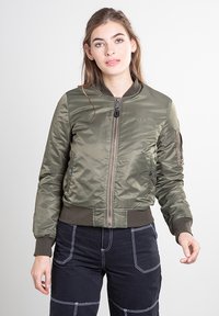 Bomberjack in olijfgroen gemaakt van glanzende, gequiltte stof. Voorzien van een ritssluiting aan de voorkant, geribbelde manchetten en een zak met klep op de mouw.