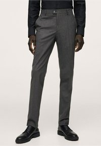 Graue maßgeschneiderte Hosen aus strukturiertem Stoff, mit flacher Vorderseite, Gürtelschlaufen und Knopfverschluss, kombiniert mit schwarzen Schnürschuhen.