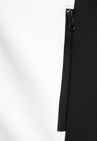 Indumento in bianco e nero con una cerniera visibile su una sezione in tessuto nero, caratterizzato da una texture liscia e dettagli di cucitura a contrasto.