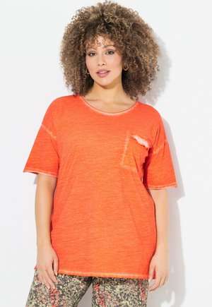 Lys orange kortærmet T-shirt med en afslappet pasform, rund halsudskæring og en lille brystlomme. Blød, tekstureret stof med frynset kanter.
