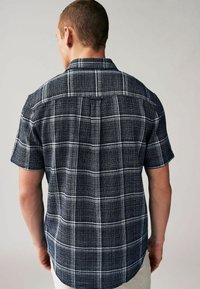 Camisetta a maniche corte a quadri in navy e bianco, con tessuto testurizzato, motivo a check sottile e dettaglio sul yoke posteriore.