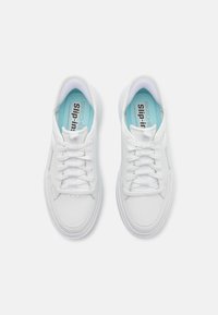Baskets blanches avec un dessus en cuir lisse, œillets assortis et une semelle intérieure bleu clair présentant le texte "SKECHERS slip-in."