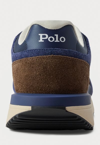 Adidași bleumarin cu accente de toc din suede maro, panouri din plasă și logo alb pe toc. Talpă texturată pentru aderență.