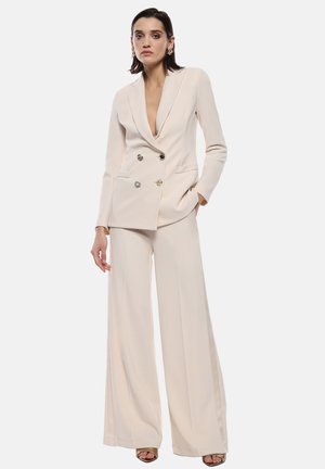 Blazer beige doppiopetto con rever a punte, pantaloni coordinati svasati e bottoni con accenti dorati, realizzato in tessuto morbido.