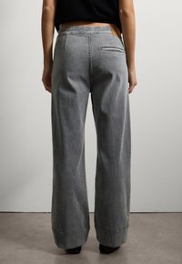 Grijze wijde jeans gemaakt van denim, met een hoge tailleband, subtiele stiksels en een enkele achterzak met een leren accent.