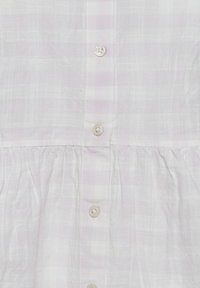 Robe en lin blanc avec des rayures horizontales discrètes, dotée d'une fermeture à boutons sur le devant et d'une taille froncée. Texture lisse et quatre boutons transparents.