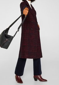 Pullover kaksirivinen takki tekstuuritetusta tummasta punaisesta ja laivastonsinisestä kankaasta, jossa on napit ja kaksi sivutaskua. Yhdistetty laivastonsinisiin samettihousuihin ja burgundin värisiin nilkkureihin.