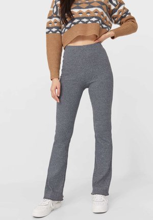 Graue gerippte Schlagleggings aus dehnbarem Stoff, mit hoher Taille und kombiniert mit einem gemusterten, kurzen Pullover.