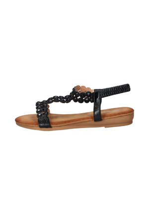 Zwarte platte sandaal met gevoerde bruine zool, elastische enkelband en decoratieve zwarte kralenbandjes over de voet.