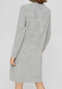 Robe en tricot gris avec ourlet et poignets côtelés. Présente un motif géométrique texturé au dos. Design mi-long. Matière douce.