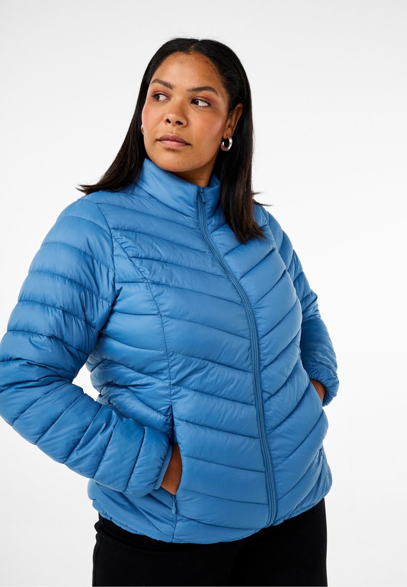 Giacca a vento blu con colletto alto, motivo a trapuntatura orizzontale e diagonale, e zip frontale; presenta due tasche laterali.