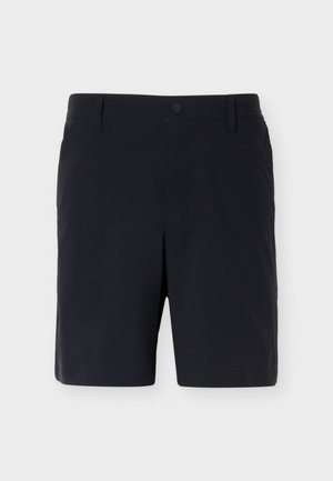 Mustad, kohandatud, põlveni ulatuvad lühikesed püksid vööaasade ja eespool oleva nupu kinnitusega heleda halli tausta vastu.