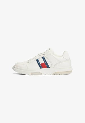 Weiße Sneaker mit einem glatten Leder-Oberteil, runder Zehenpartie und drei farbigen Streifen: Navy, Rot und Weiß, mit Branding an der Seite.
