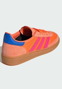 Orange suede sneaker with pink and blue accents, featuring three stripes, a gum outsole, and a rounded toe design.