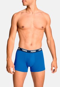 Caleçons en coton bleu avec une coupe ajustée et une ceinture noire contrastante portant le logo "PUMA" en blanc.