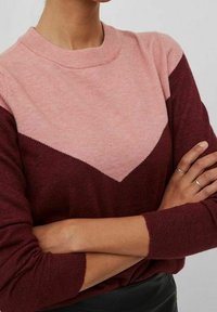 Stickad tröja med en chevron-design i rosa och vinröd. Ribbad rund halsringning och långa ärmar med texturerad finish.