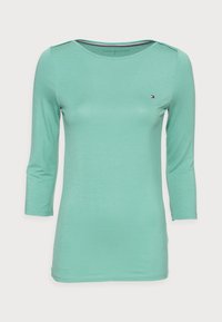 Mintgrünes Langarmshirt aus glattem Stoff, mit Rundhalsausschnitt und einem kleinen Logoakzent auf der Brust.