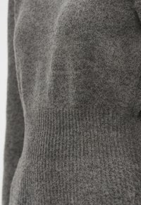 Pulôver cinza de malha, feito de lã macia, apresentando um padrão texturizado de nervuras na cintura e um tecido superior suave com uma silhueta ajustada.