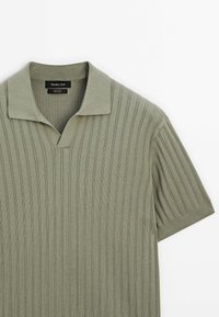 Polo en maille vert olive clair à manches courtes avec texture côtelée verticale et col ouvert, étiqueté Massimo Dutti, 100 % coton.