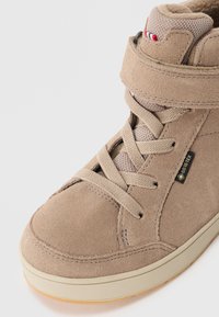 Bež semis kožne visoke teniske sa vezicama, čičak trakama, mrežastim jezikom i malom oznakom od GORE-TEX tkanine sa strane.