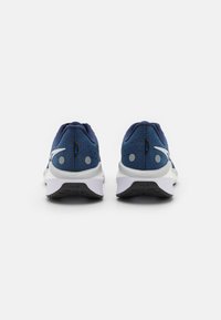 Scarpe da atletica blu con un upper testurizzato, accentuate da dettagli bianchi, un colletto imbottito e una suola in gomma nera, con particolari riflettenti tondi.