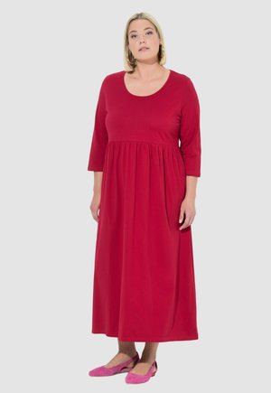 Robe longue rouge en tissu doux avec un décolleté rond et des manches trois-quarts, présentant une taille froncée et un ourlet long au sol.