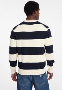 Gestreifter Strickpullover in Marineblau und creme mit Rundhalsausschnitt und gerippten Bündchen. Verfügt über Raglanärmel und eine strukturierte Oberfläche.