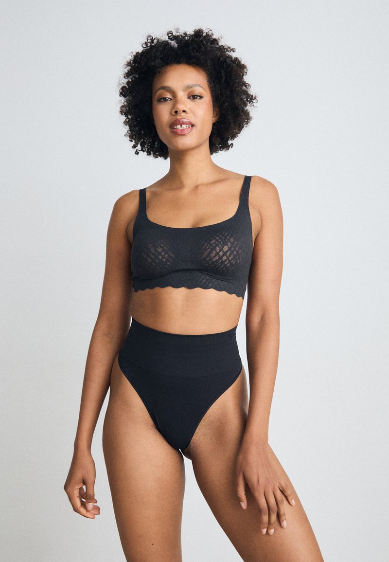 Svart undertøyssett bestående av en strukturert bralette med brede stropper og høytlivs truse. Glatt, elastisk stoff med bølgede kanter.