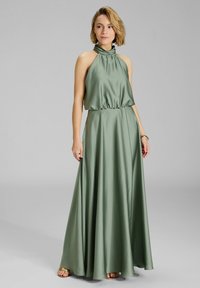 Vihreä satiininen maksimekko, jossa on kietaisukaula, joustava vyötärö ja levenevä hame, luoden sulavan ja elegantin siluetin.