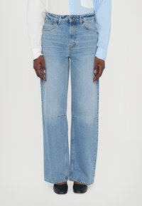 Light blue wide-leg jeans with a faded finish, featuring a high waist, traditional five-pocket design, and subtle stitching details.