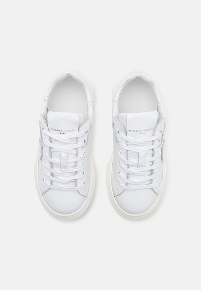 Baskets en cuir blanc avec bout rond, lacets à l'avant et design minimal. Accents texturés et logo sur le côté. Semelle en caoutchouc et rembourrage.