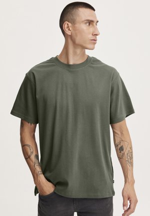 Camiseta de algodón verde oliva con mangas cortas, cuello redondo y un ajuste relajado. Presenta una textura suave y un ligero estiramiento.