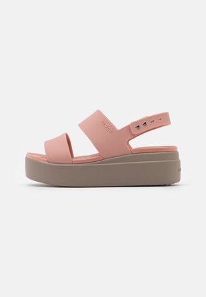 Sandale plateforme rose avec deux larges brides et une bride arrière avec des détails de boutons argentés, sur une semelle beige épaisse.