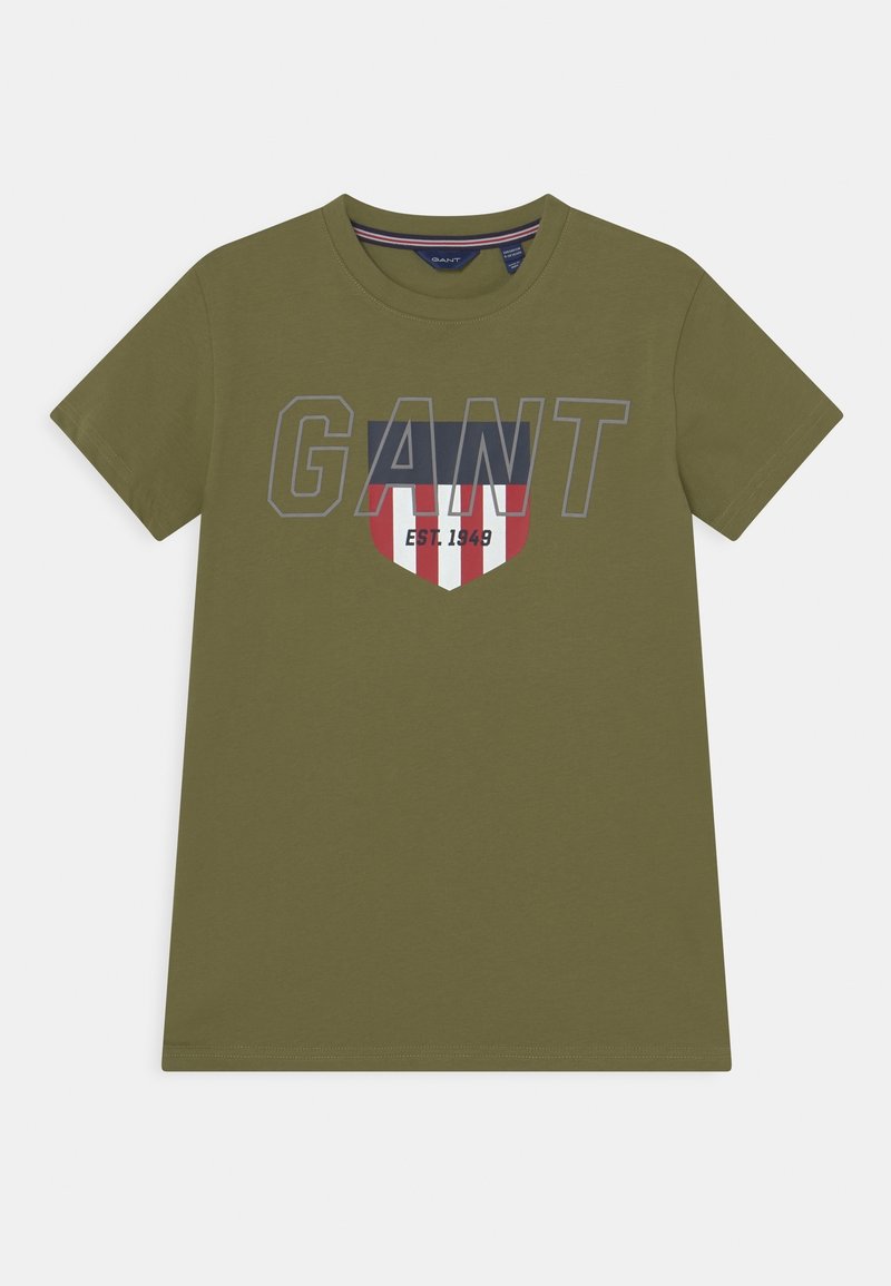 Oliwkowy t-shirt wykonany z bawełny, z napisem "GANT" w szarym kolorze, logo w kształcie tarczy z czerwonymi, białymi i niebieskimi akcentami oraz krótkimi rękawami.