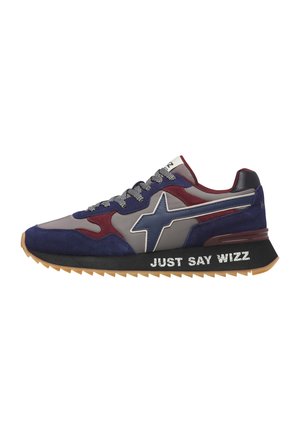 Sneaker con pannelli blu navy, grigio e bordeaux, logo a stella sul lato, suola nera con testo "JUST SAY WIZZ," e lacci decorati.