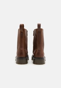 Botas de cuero marrón hasta el tobillo con un acabado suave, que presentan una cremallera lateral, una lengüeta y una suela de goma gruesa. Diseño estándar con detalles de costura.