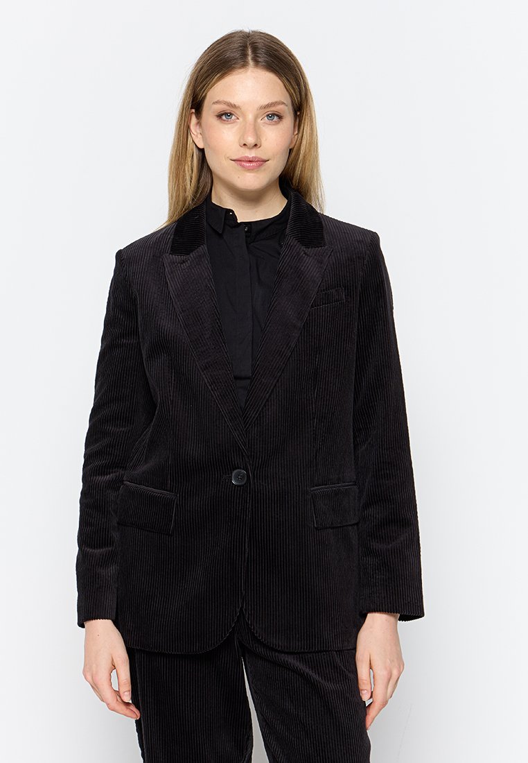 Blazer en velours côtelé noir avec des revers crantés, fermeture à un bouton et deux poches avant. Tissu texturé avec des côtes verticales.