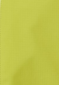 Limegrønt stof med et subtilt firkantet gittermønster og en syet lodret søm på venstre kant.